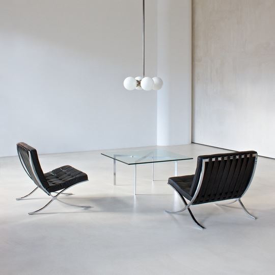 Two Barcelona Chairs in a room with a Barcelona Table